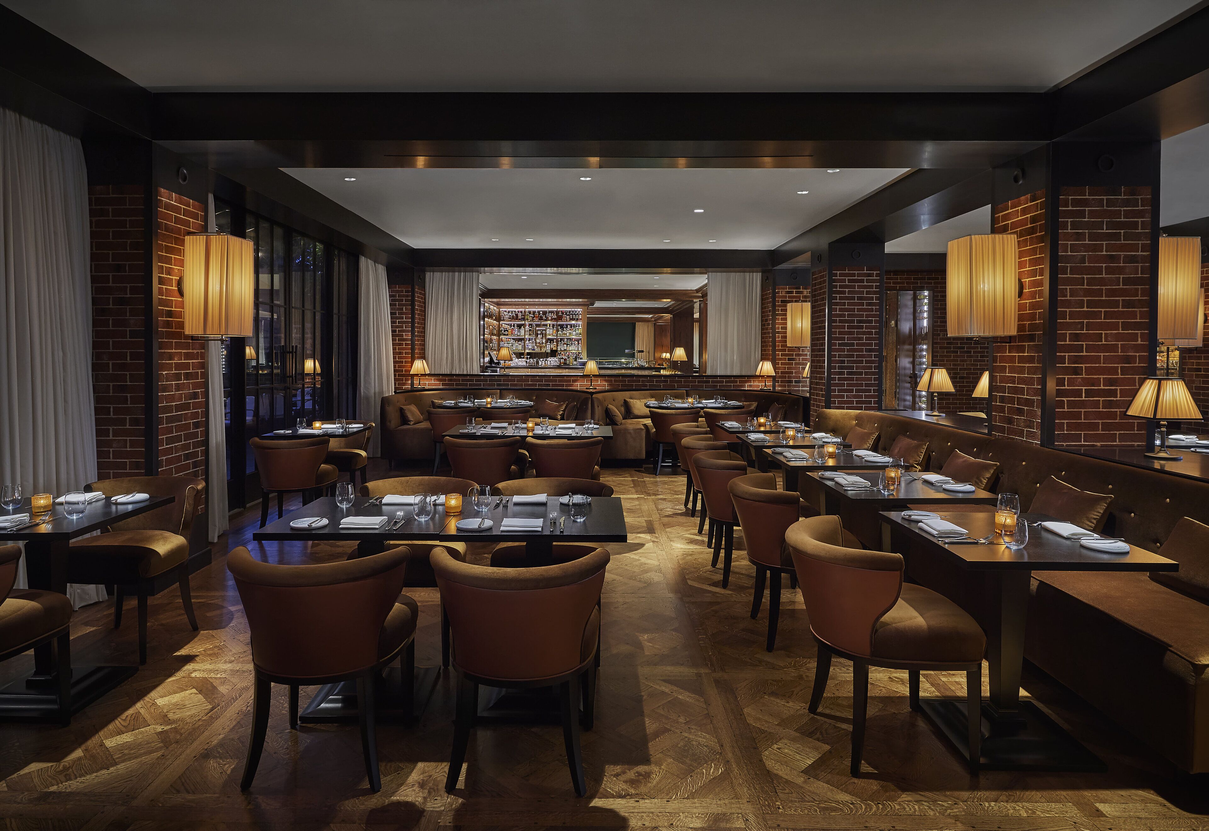 A restaurant with multiple tables and booths, brick walls, and warm lighting.