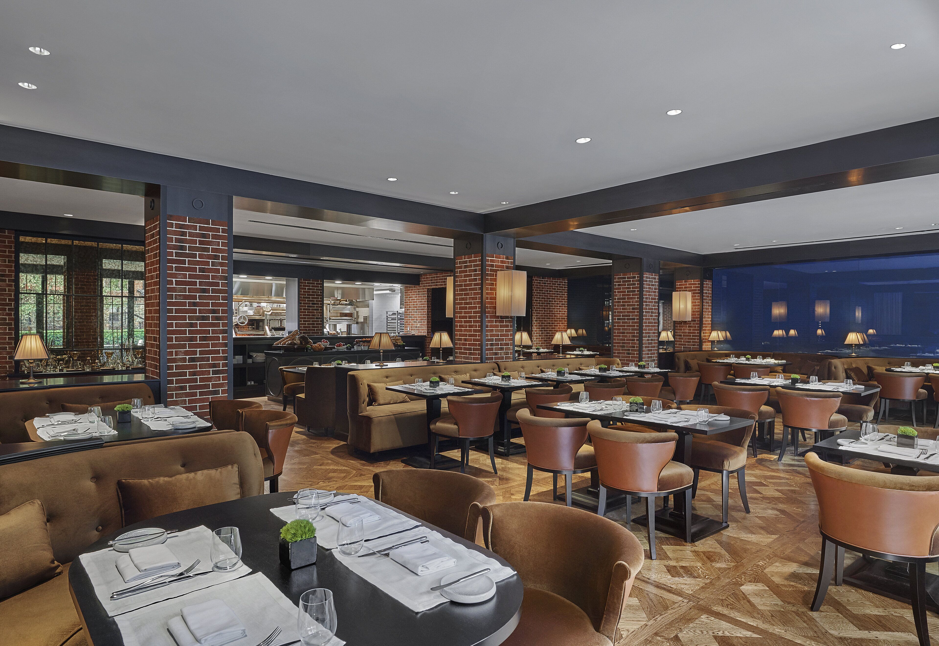 Een modern restaurant met bakstenen details, lederen zitplaatsen en een combinatie van tafels en ruimere zitplekken.
