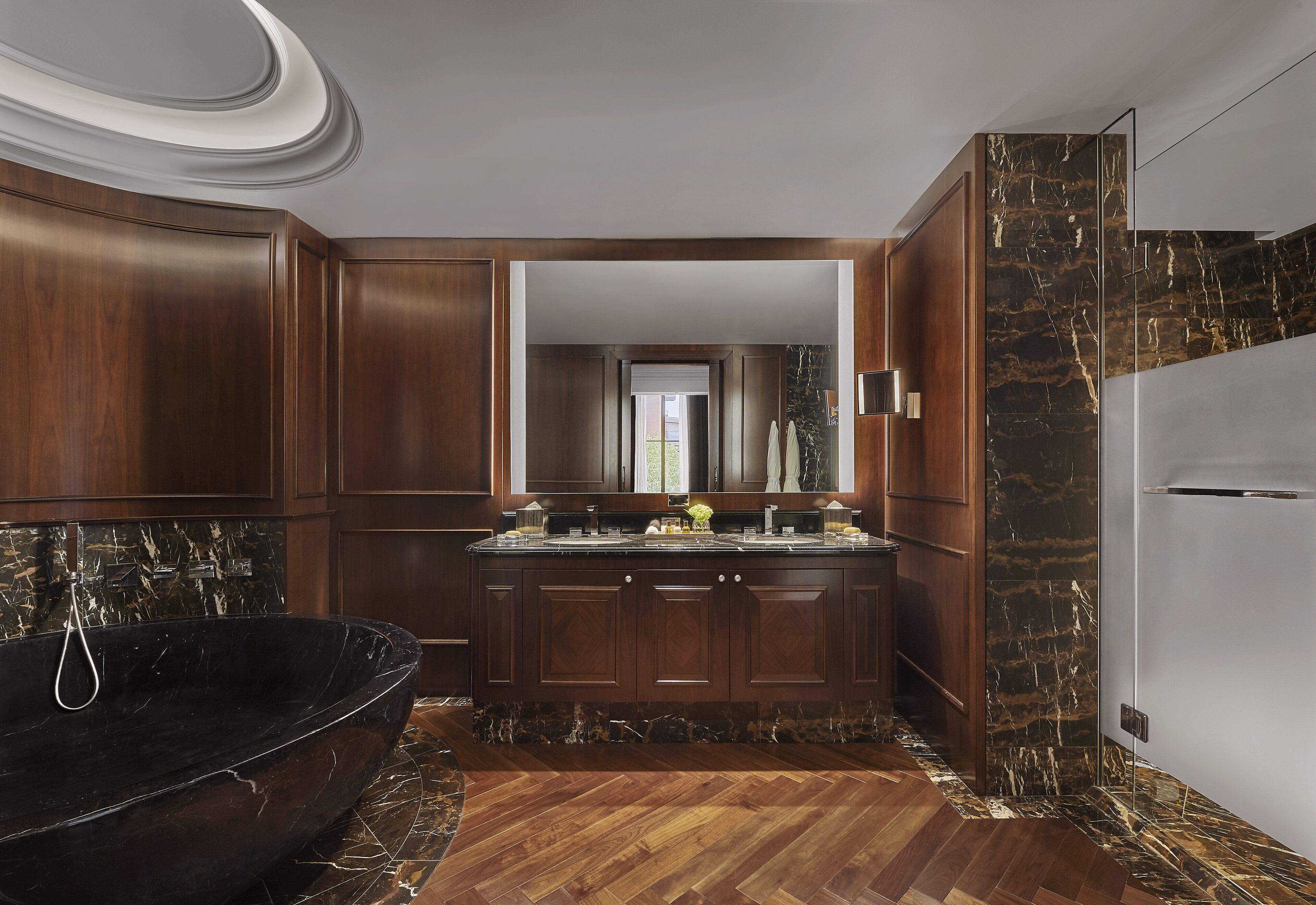 A modern kitchen with dark wood cabinets, a black bathtub, and a marble backsplash.