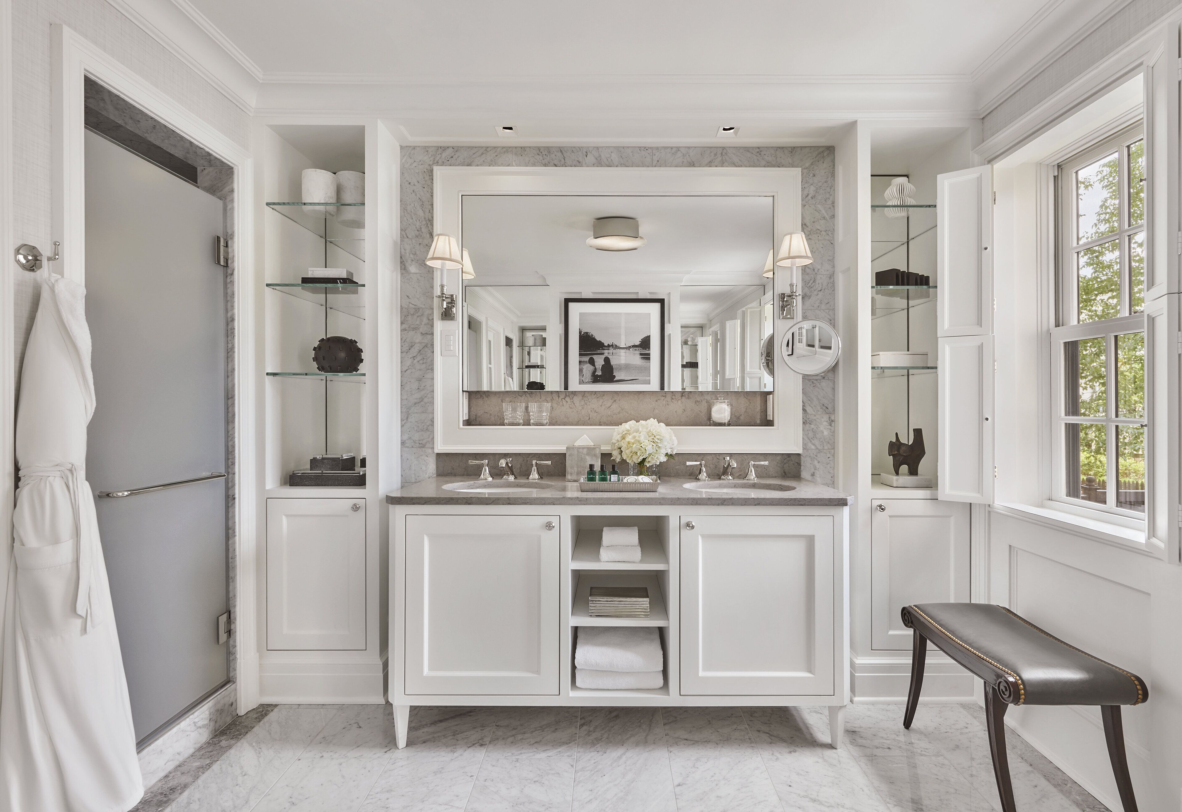 Une salle de bain spacieuse avec un meuble-lavabo à deux vasques, un grand miroir et un banc.