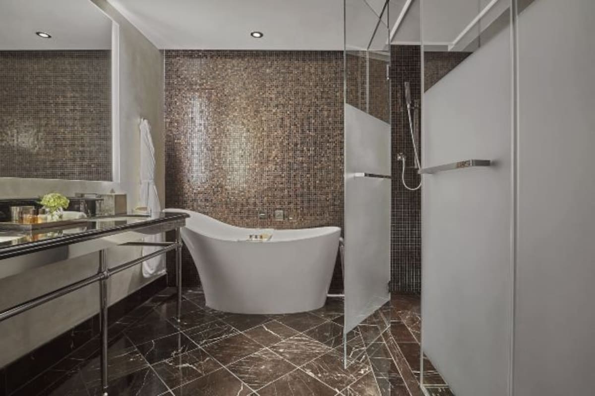 A modern bathroom with a freestanding bathtub, a glass shower enclosure, and a marble-tiled floor.