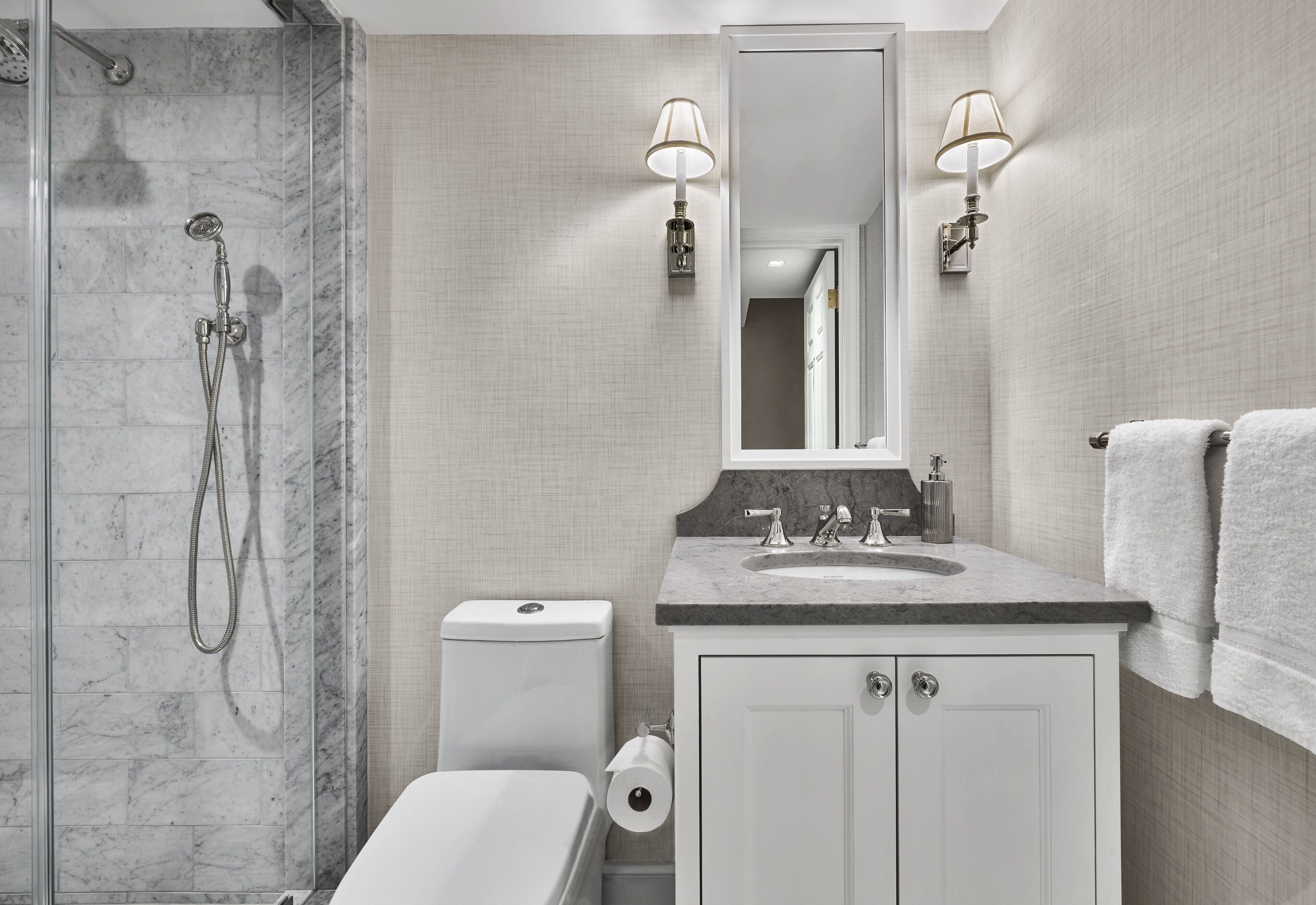 A modern bathroom with a shower, toilet, sink, and mirror.