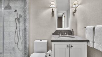 A modern bathroom with a shower, toilet, sink, and mirror.