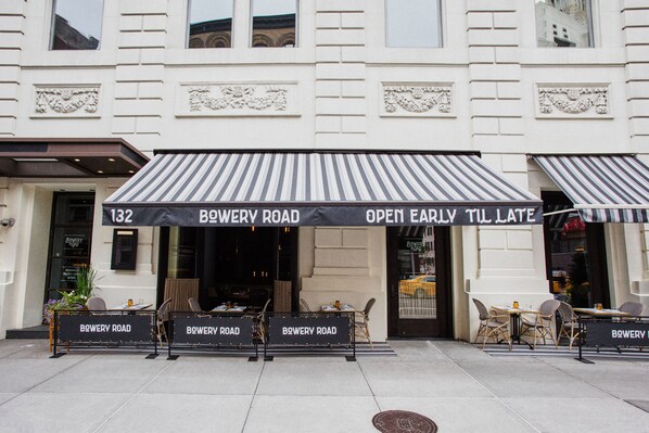 Un edificio con un cartel que dice "BOWERY ROAD OPEN EARLY TIL LATE" y el número "132" sobre la entrada.