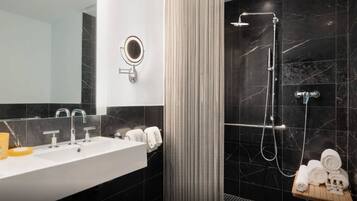 A modern bathroom with a large mirror, a sink, and a shower area.