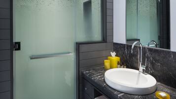 A modern bathroom with a glass shower enclosure, a white sink, and a marble countertop.