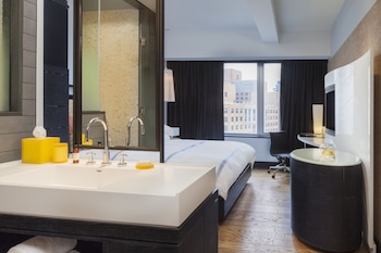 A modern hotel room with a wine rack, a flat-screen TV, and a view of the city through large windows. at Hyatt Union Square New York