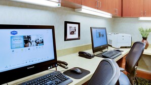 Un bureau d’hôtel équipé de trois écrans d’ordinateur, d’un ordinateur de bureau, d’un téléphone et d’une imprimante.