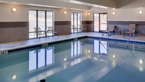 Une piscine avec des chaises longues et un mur carrelé.