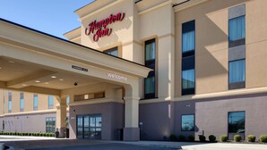 Un hôtel Hampton Inn avec une enseigne bien visible, une enseigne indiquant « Bienvenue » et une autre indiquant « Hauteur maximale : 14 pieds ».