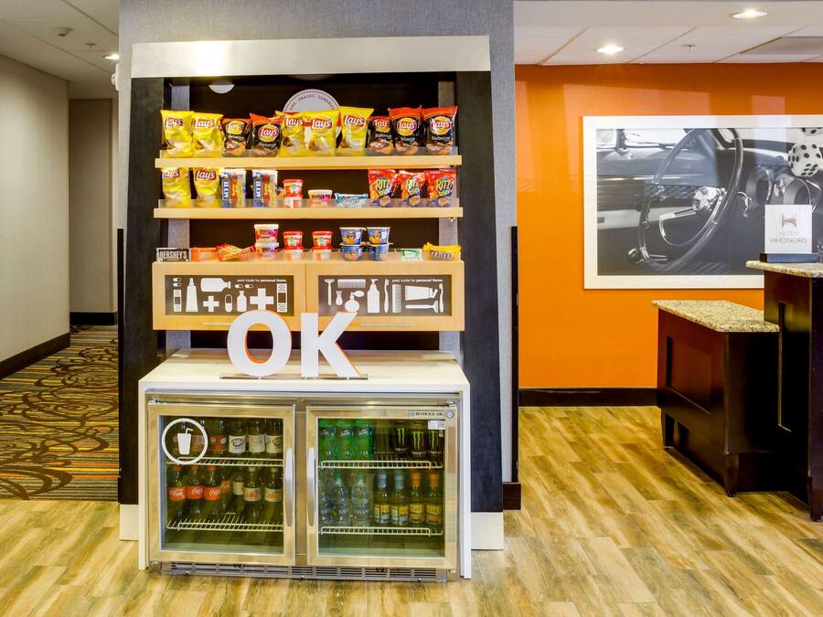 A vending machine with snacks and beverages, a sign with the letter 'OK', and a wall with a car advertisement.