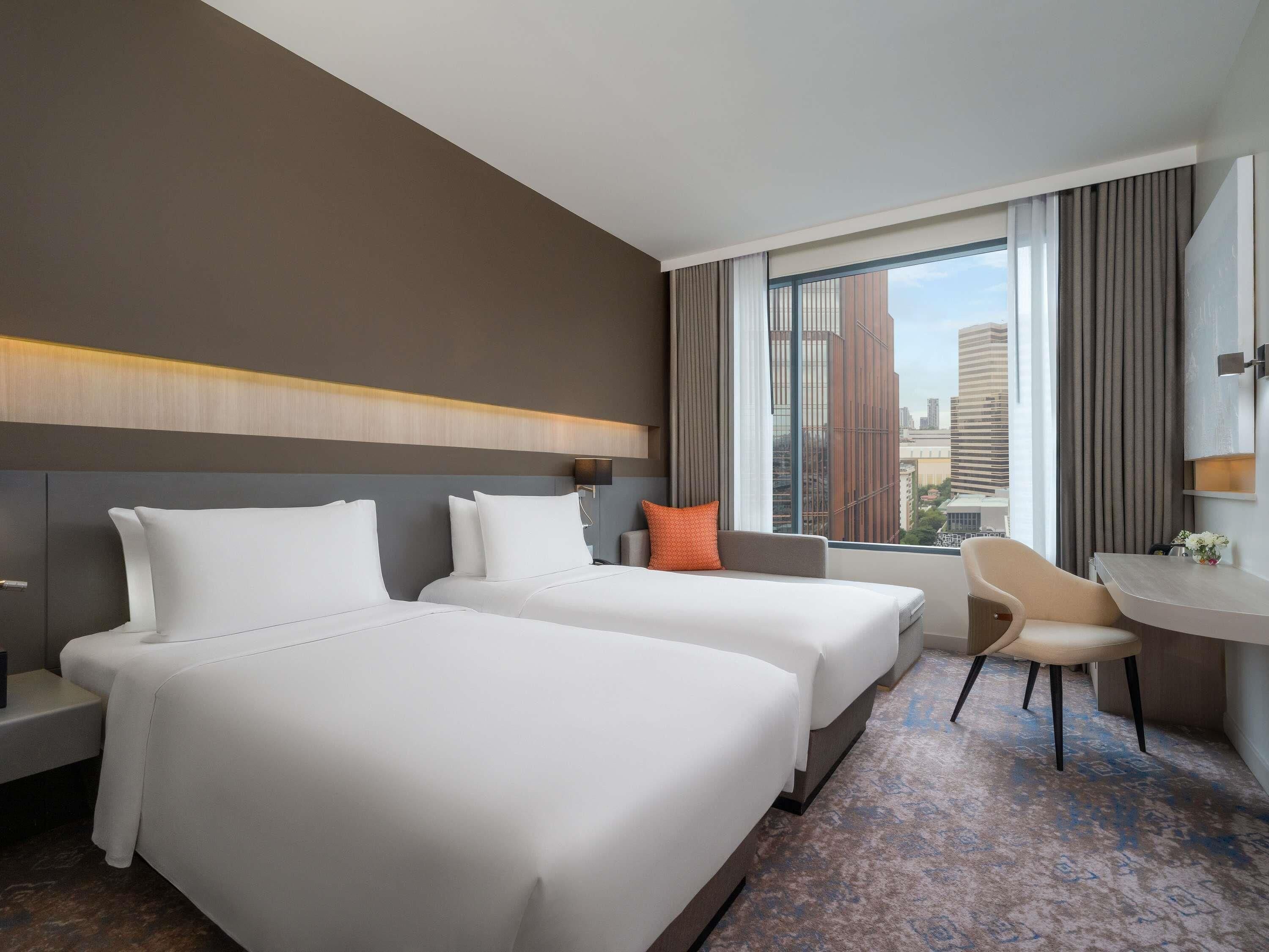Une chambre d’hôtel avec deux lits, un bureau et une chaise.