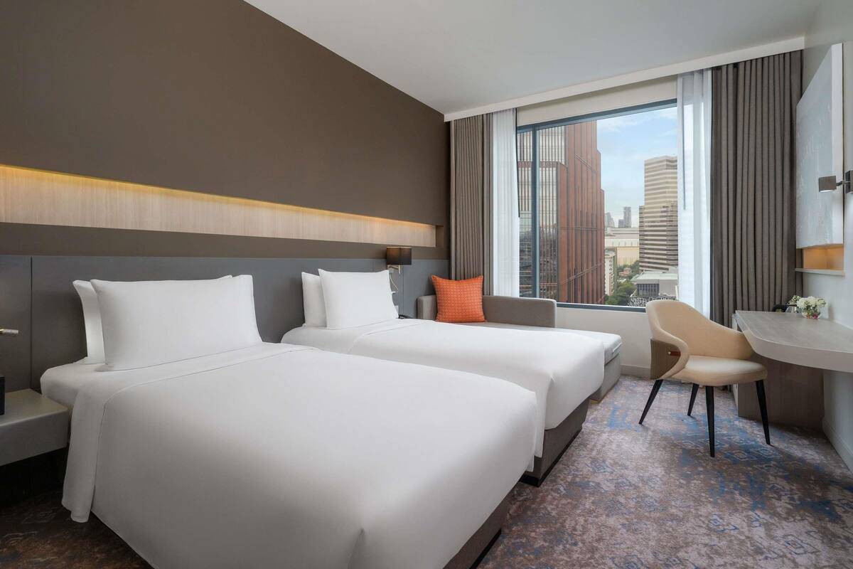 A hotel room with two beds, a desk, and a chair.