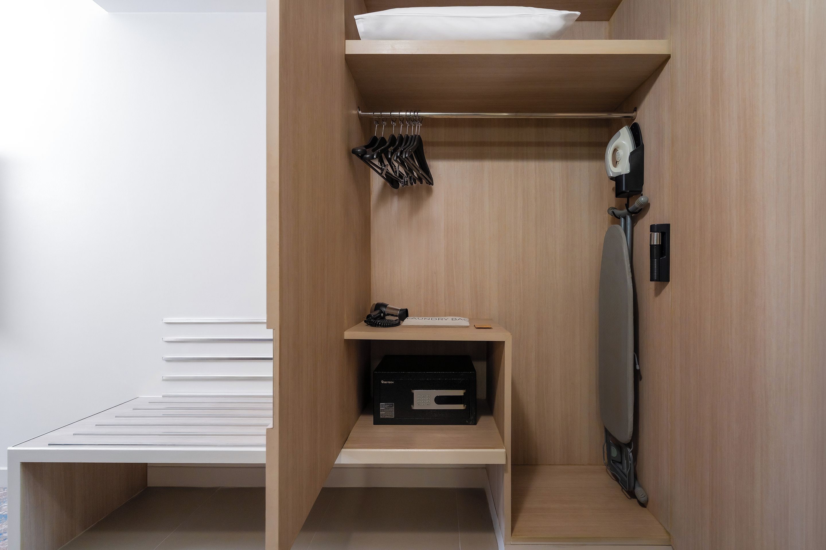 Un baño moderno y compacto con tocador de madera, toallero y secador de pelo incorporado.