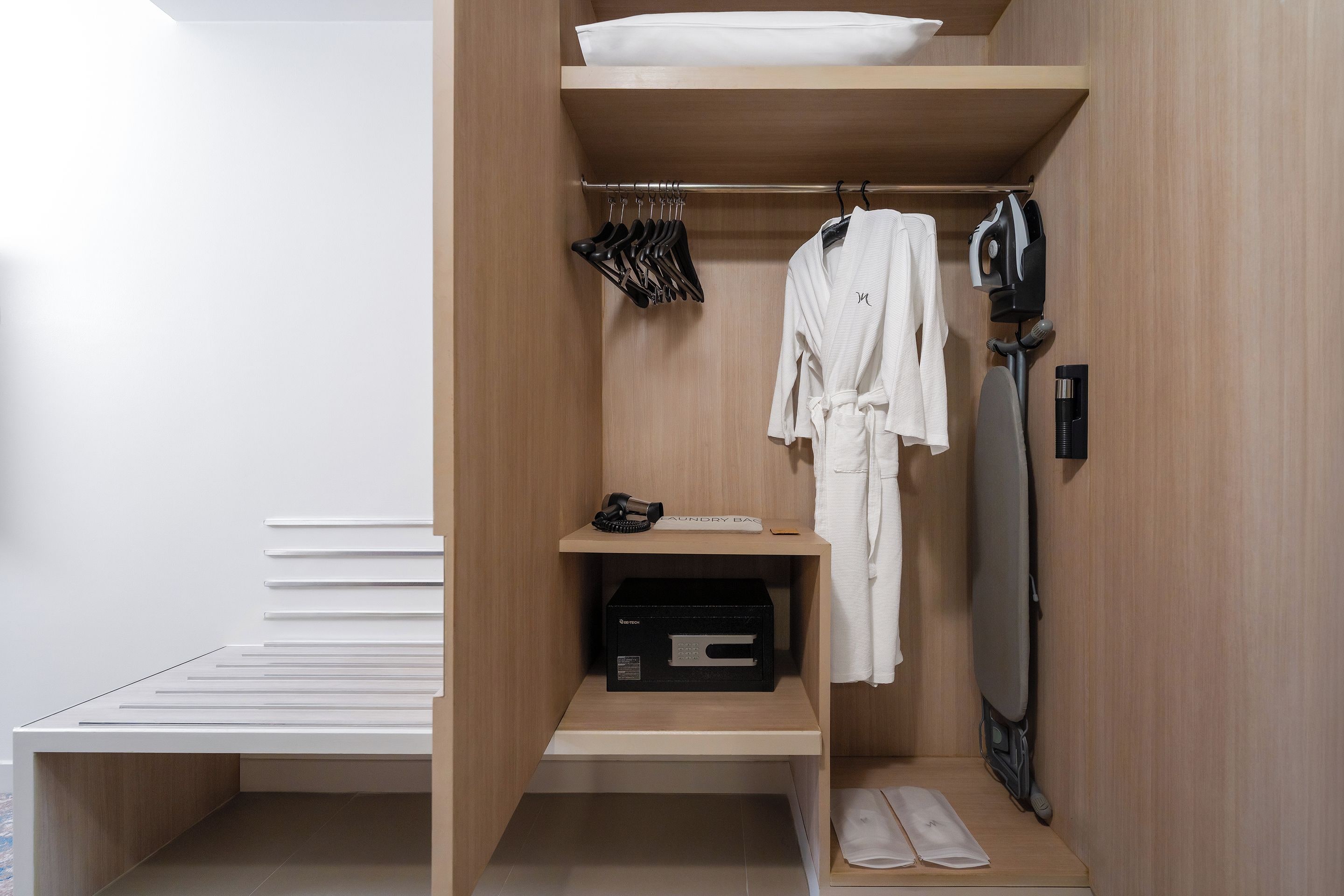 Ein begehbarer Kleiderschrank mit Holzregalen, einer Kleiderstange und einem Schuhregal.