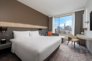 A hotel room with a large bed, a desk, a chair, a nightstand, and a city view. - Mercure Bangkok Siam (Bangkok)