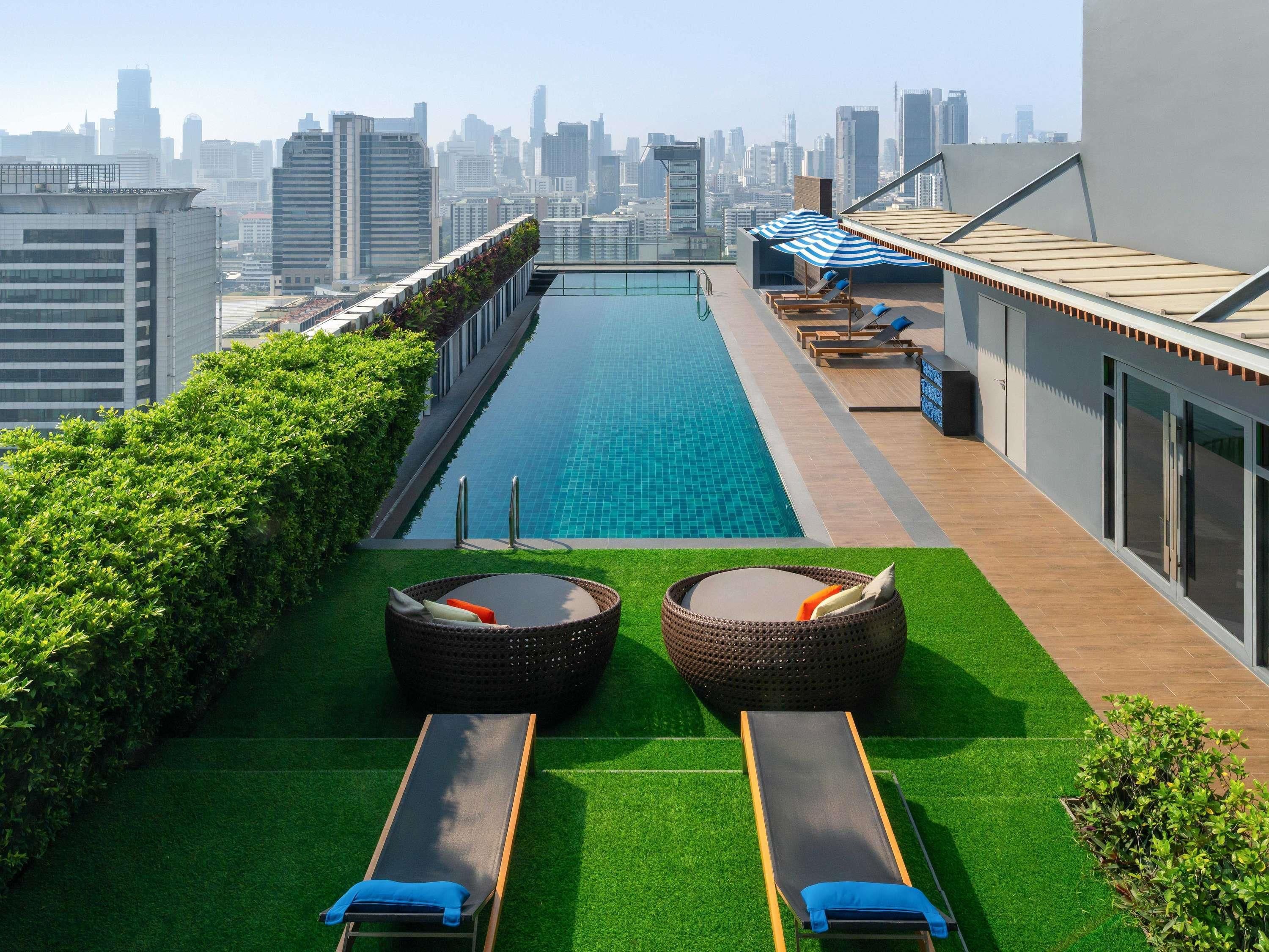 A rooftop pool with two sun loungers and a city skyline in the background.