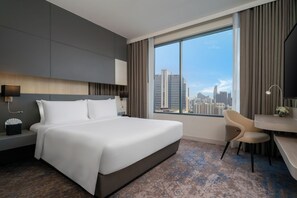 A modern hotel room with a large bed, a desk, and a view of the city skyline. - Mercure Bangkok Siam (Bangkok)