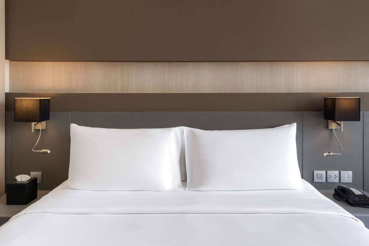 A hotel room with a large bed, two bedside lamps, a bedside phone, and a tissue box.