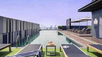 Alberca al aire libre, sombrillas en la alberca y camastros