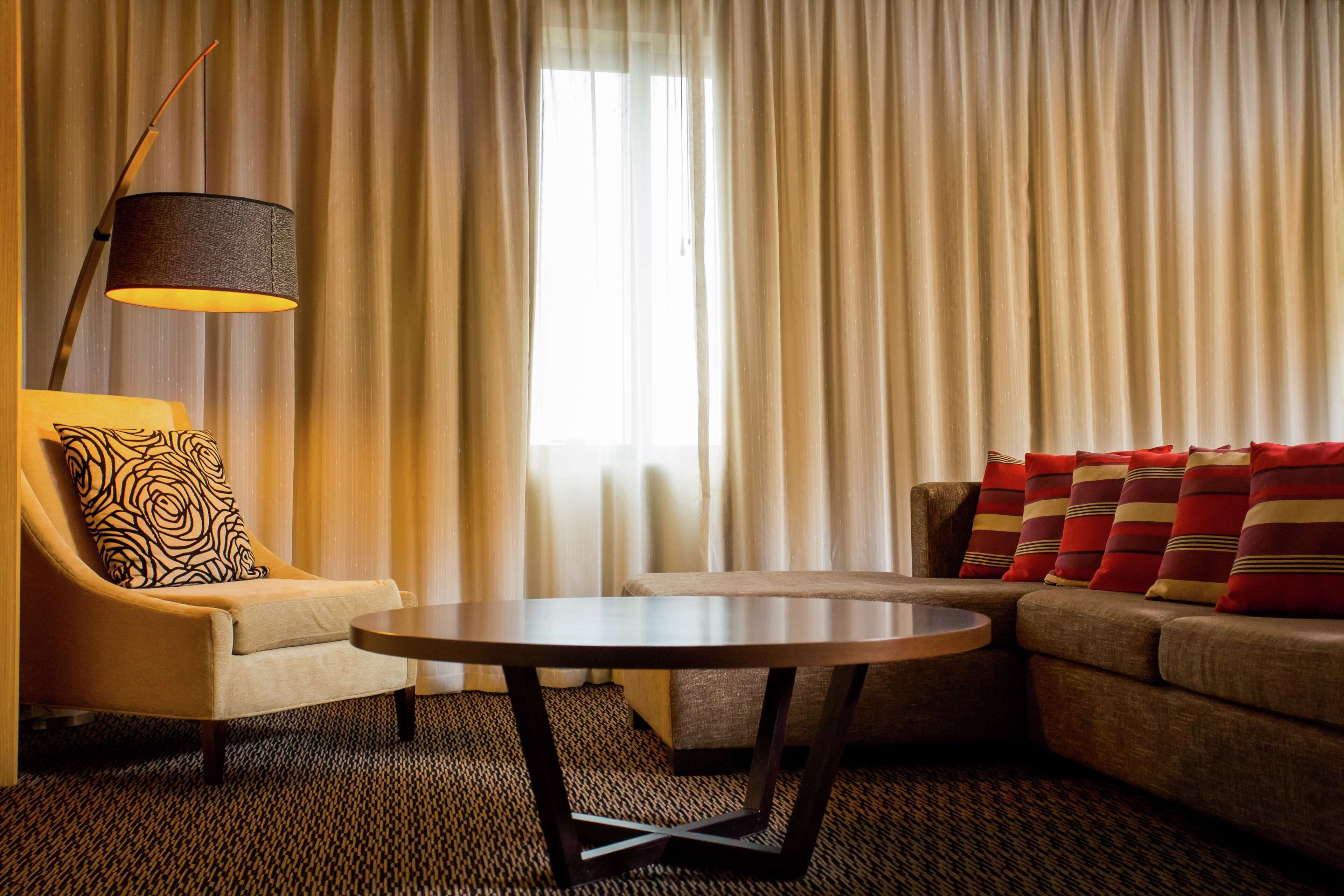 A hotel room with a sofa, armchair, and a table.