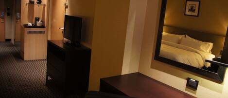 A hotel room with a bed, a desk, a television, and a wardrobe.