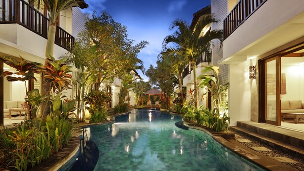 A swimming pool surrounded by lush greenery and modern architecture. - Seminyak Townhouse Apartment (Legian)