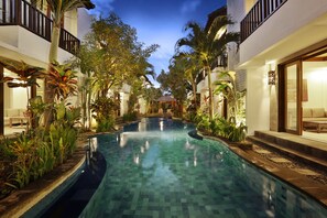 A swimming pool surrounded by lush greenery and modern architecture. - Seminyak Townhouse Apartment (Legian)