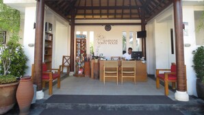 A reception area with a wooden desk, two chairs, a bookshelf, and a sign reading "Seminyak Town House". - Seminyak Townhouse Apartment (Legian)