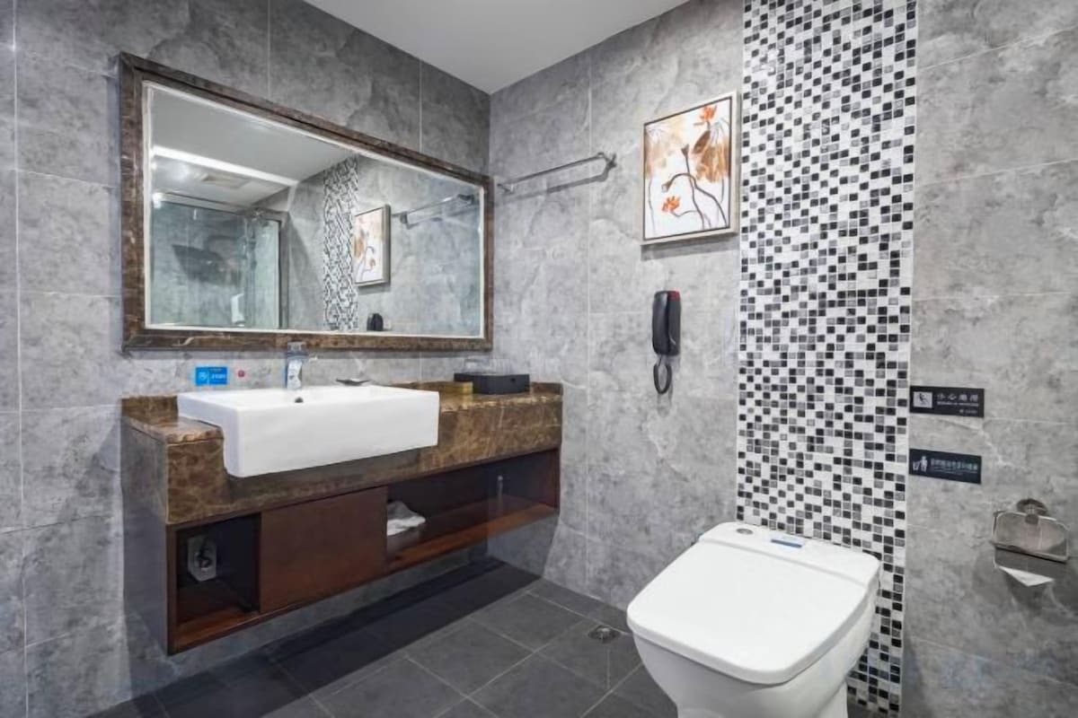 A modern bathroom with a marble sink, a toilet, and a shower area.