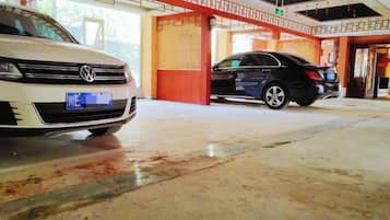 A parking area with two cars, a white and a black one, and a building entrance with a red and white color scheme.