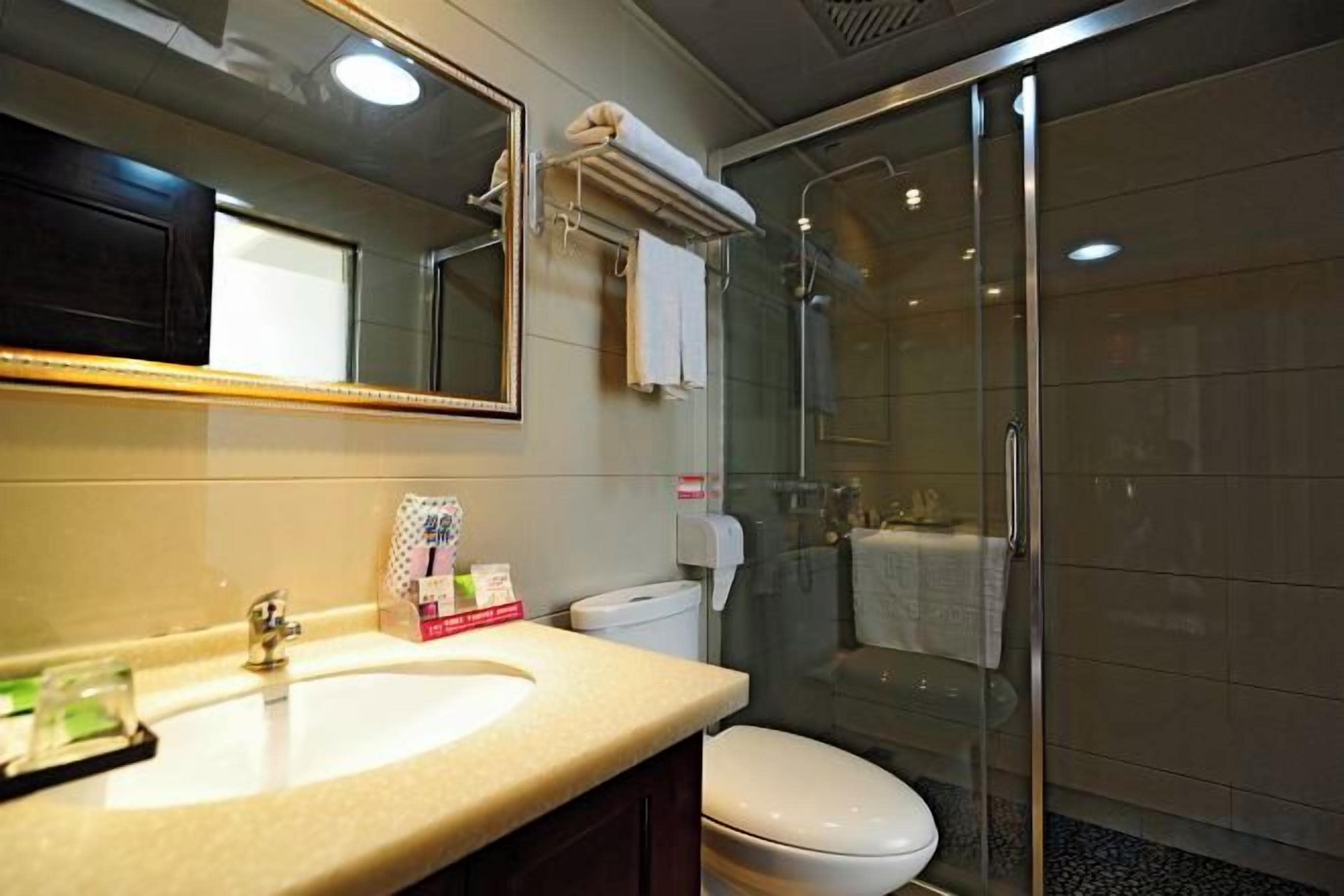 Un baño con lavamanos, inodoro y ducha con mampara de vidrio.
