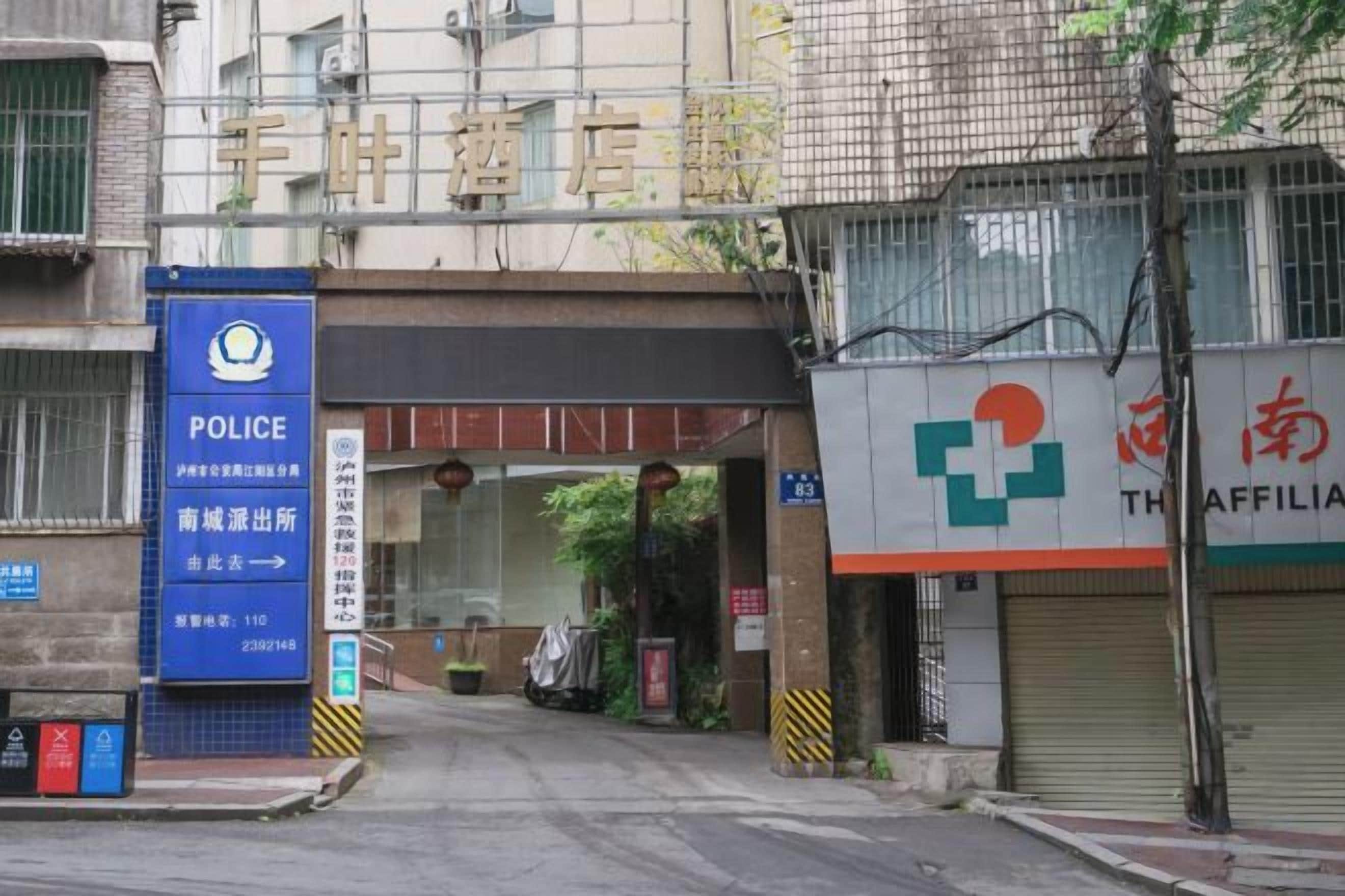 A building entrance with a police sign, a pharmacy, and a closed shop.