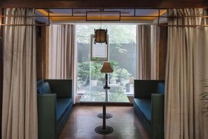 Une pièce avec un canapé, une table avec une lampe et une vue par la fenêtre.
