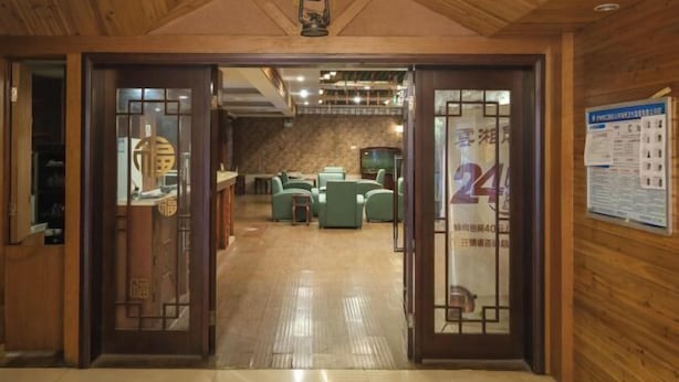 Un hall de hotel con paredes de madera y suelo de baldosas, que incluye un mostrador de recepción y una zona de estar.