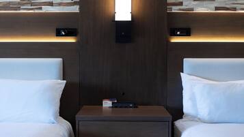 Habitación de hotel con dos camas, una mesita de noche y un aplique de pared.