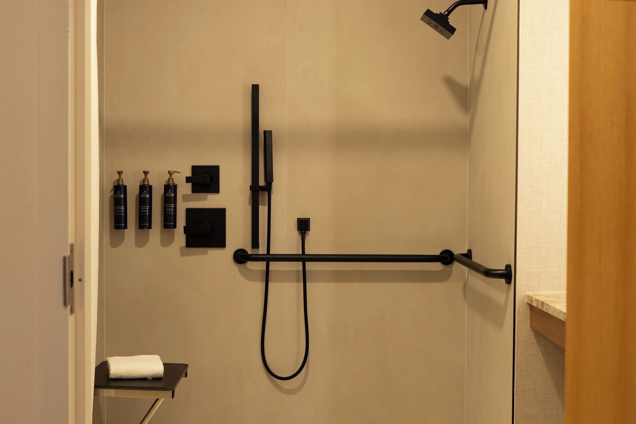 Un baño con ducha, toallero y estante con artículos de aseo.