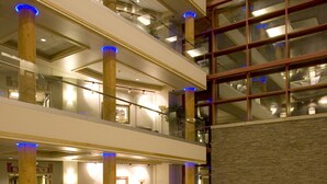 A multi-level hotel lobby with a staircase, seating areas, and a large stone wall with a decorative panel. - Little Creek Casino Resort (Shelton)