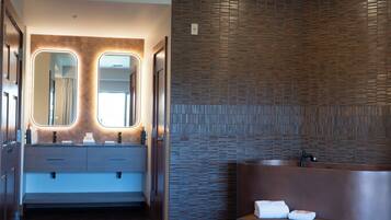 Un baño moderno con un espejo grande, un lavabo y un banco con toallas.