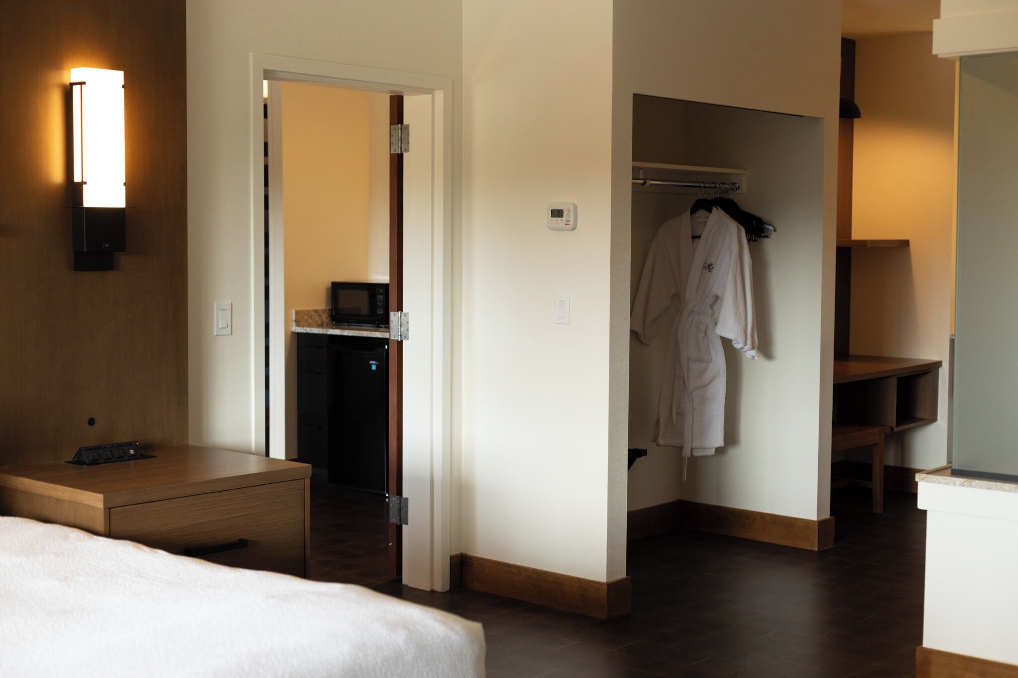 Una habitación de hotel con cama, mesita de noche, armario y un pequeño escritorio con silla.