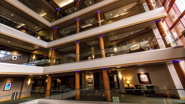 A multi-level atrium with glass railings, wooden columns, and a central staircase. - Little Creek Casino Resort (Shelton)