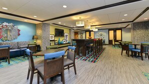 A hotel lobby with seating areas, a bar, and a television.