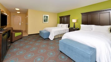 A hotel room with two beds, a TV, a desk, and a chair.