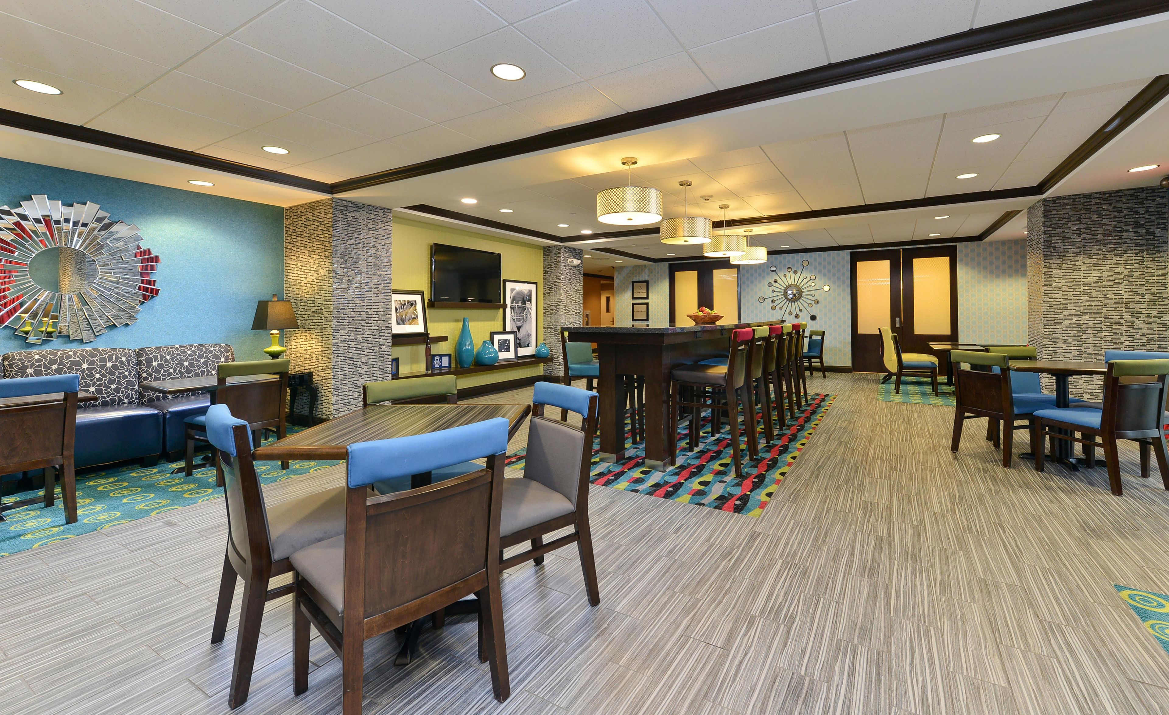 A hotel lobby with a bar area, seating arrangements, and a television mounted on the wall.