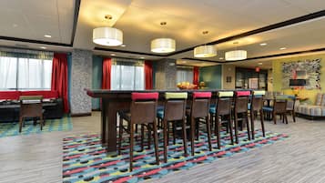 A hotel lobby with a bar area, seating, and a patterned carpet.