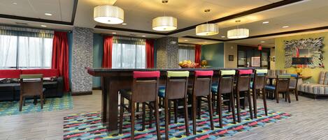 A hotel lobby with a bar area, seating, and a patterned carpet.