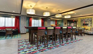 Een hotel lobby met een bar, zitplaatsen en een kamerbreed tapijt.