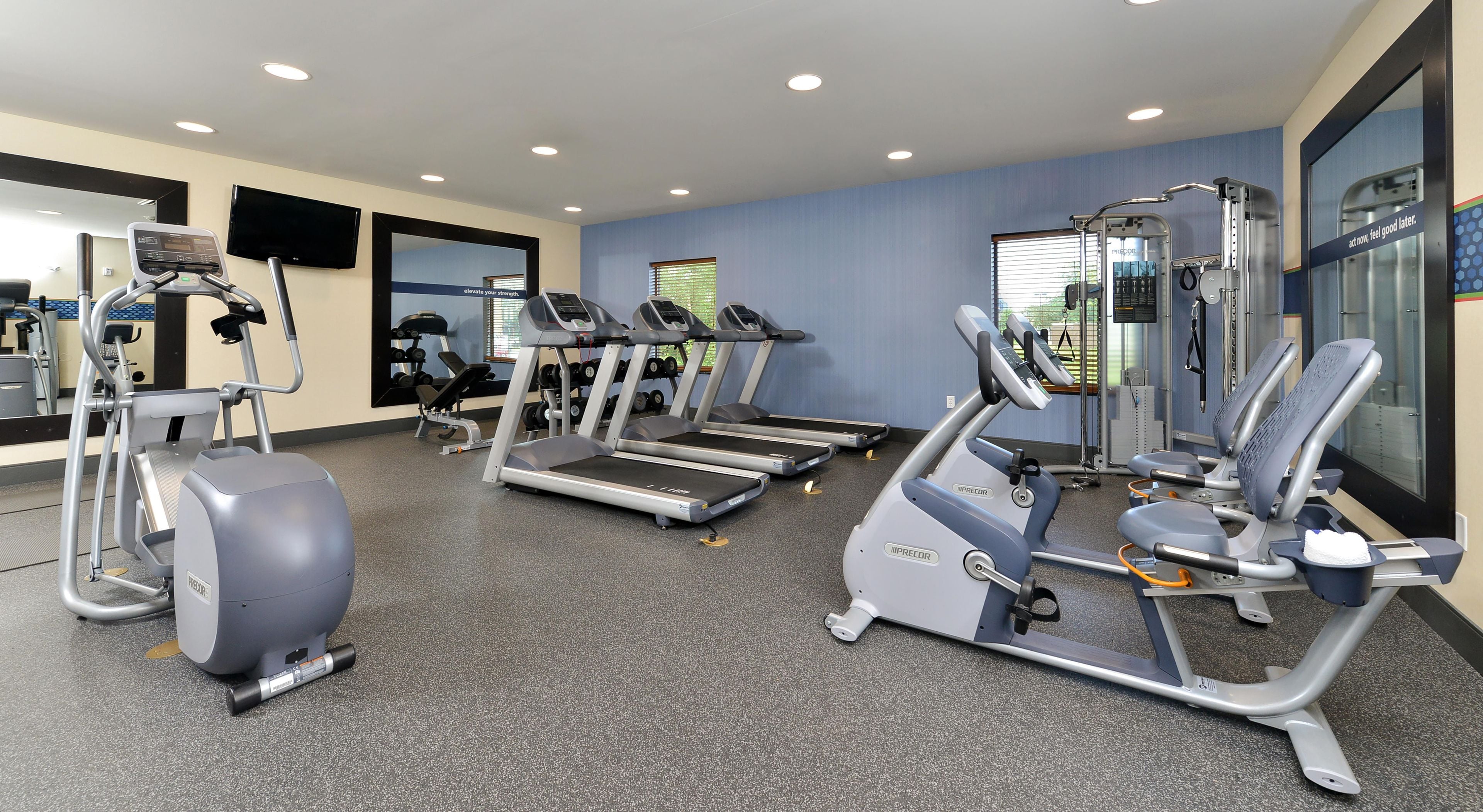 Een fitnessruimte met loopbanden, elliptische trainers en gewichthefapparatuur.