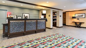 A reception area with a mosaic-patterned counter, a colorful rug, and a framed welcome sign.