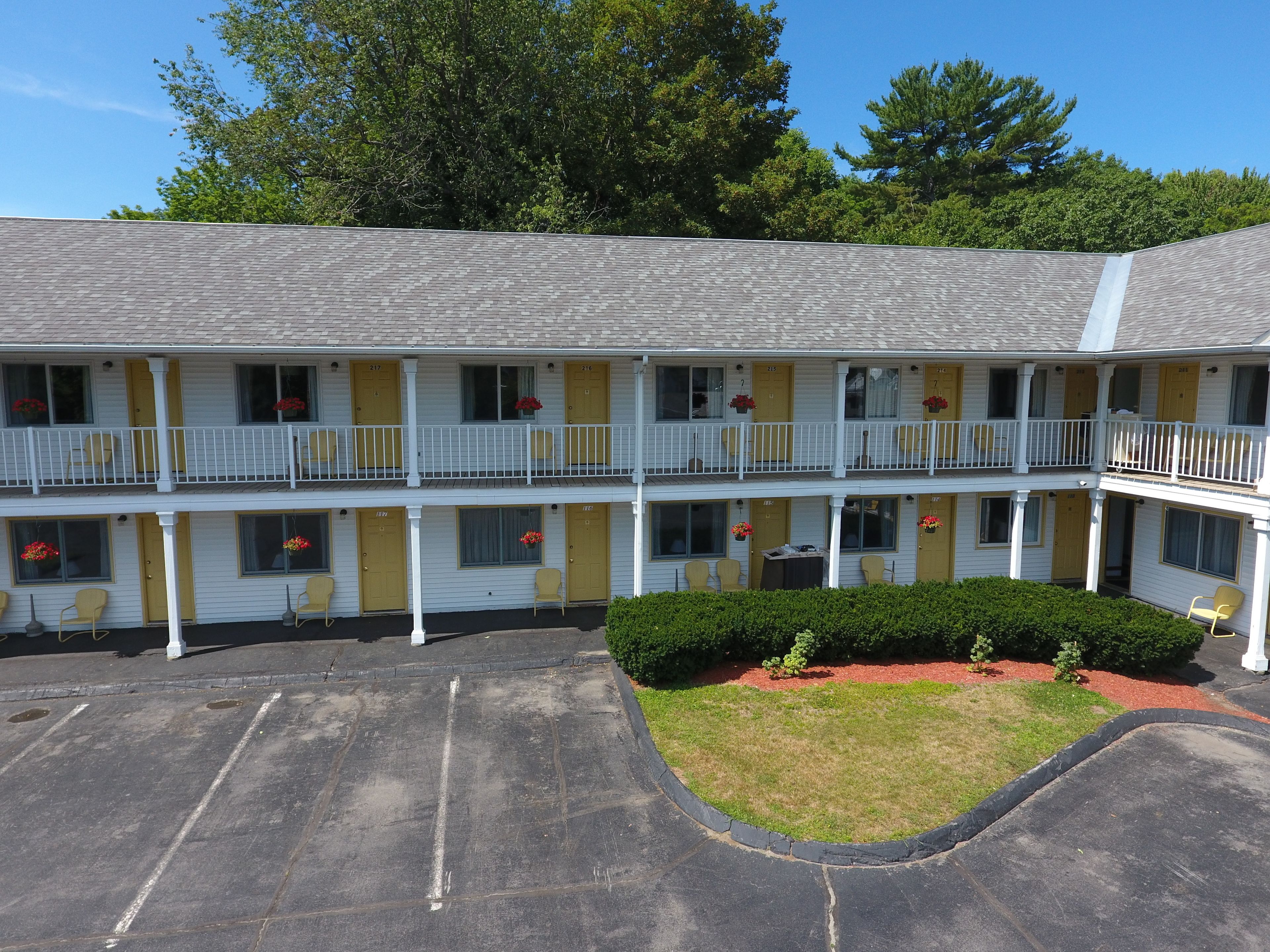 A two-story motel with a central courtyard, multiple balconies, and a parking lot.